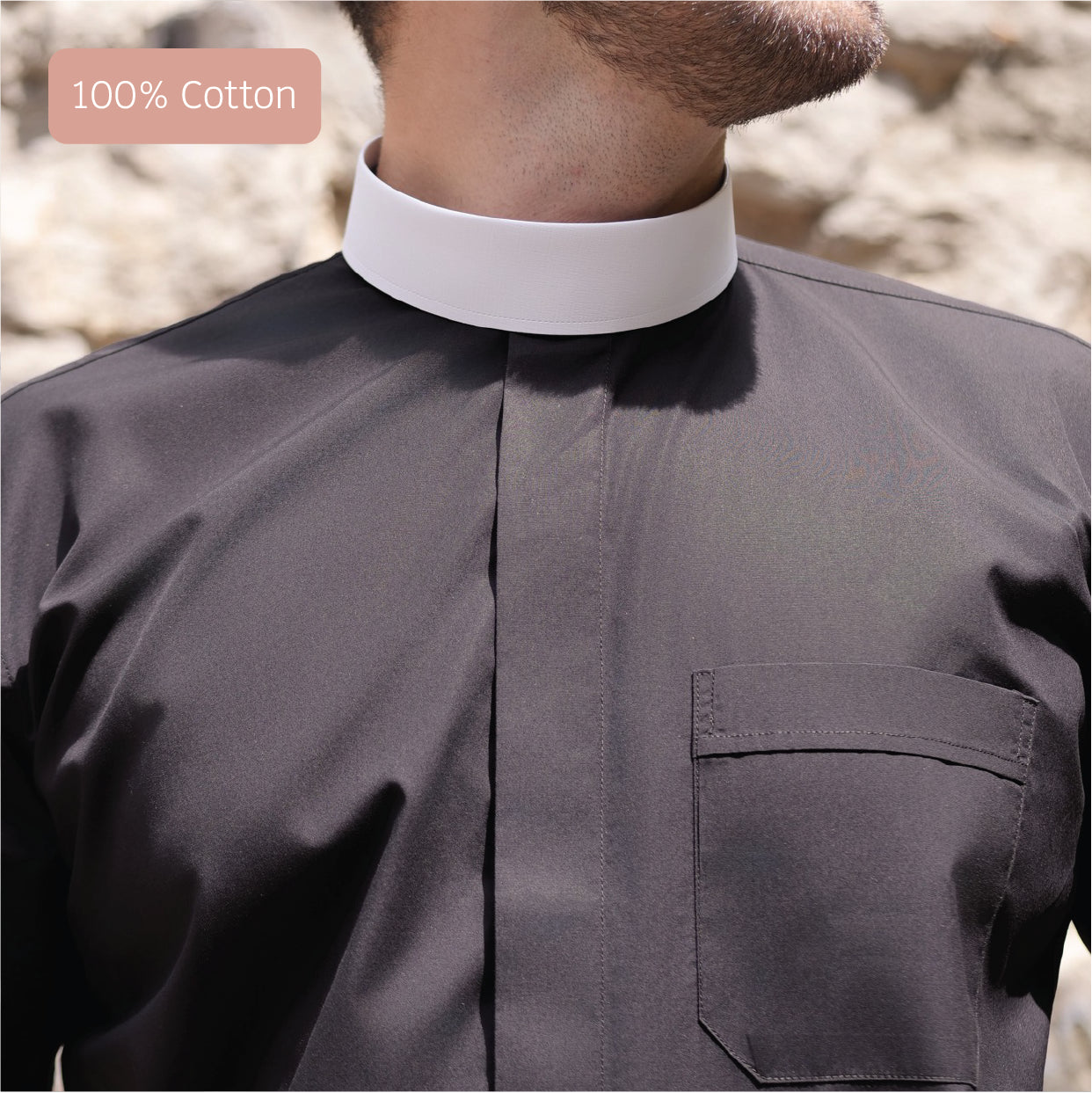 Close-up of a man wearing a black clergy shirt made of 100% cotton, featuring a white collar and pocket detail.