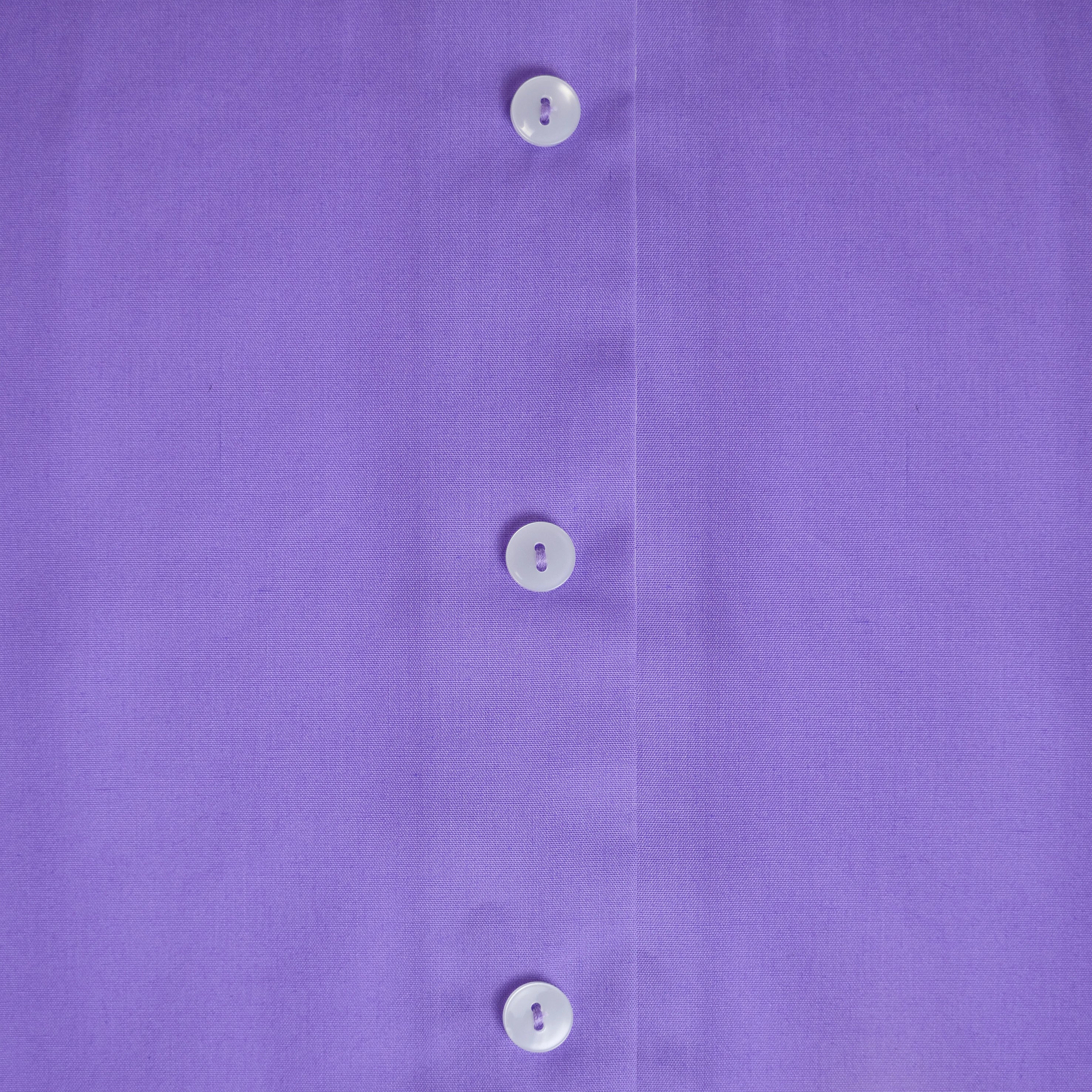 Close-up of Women's Tonsure Clergy Shirt buttons on a purple fabric background.
